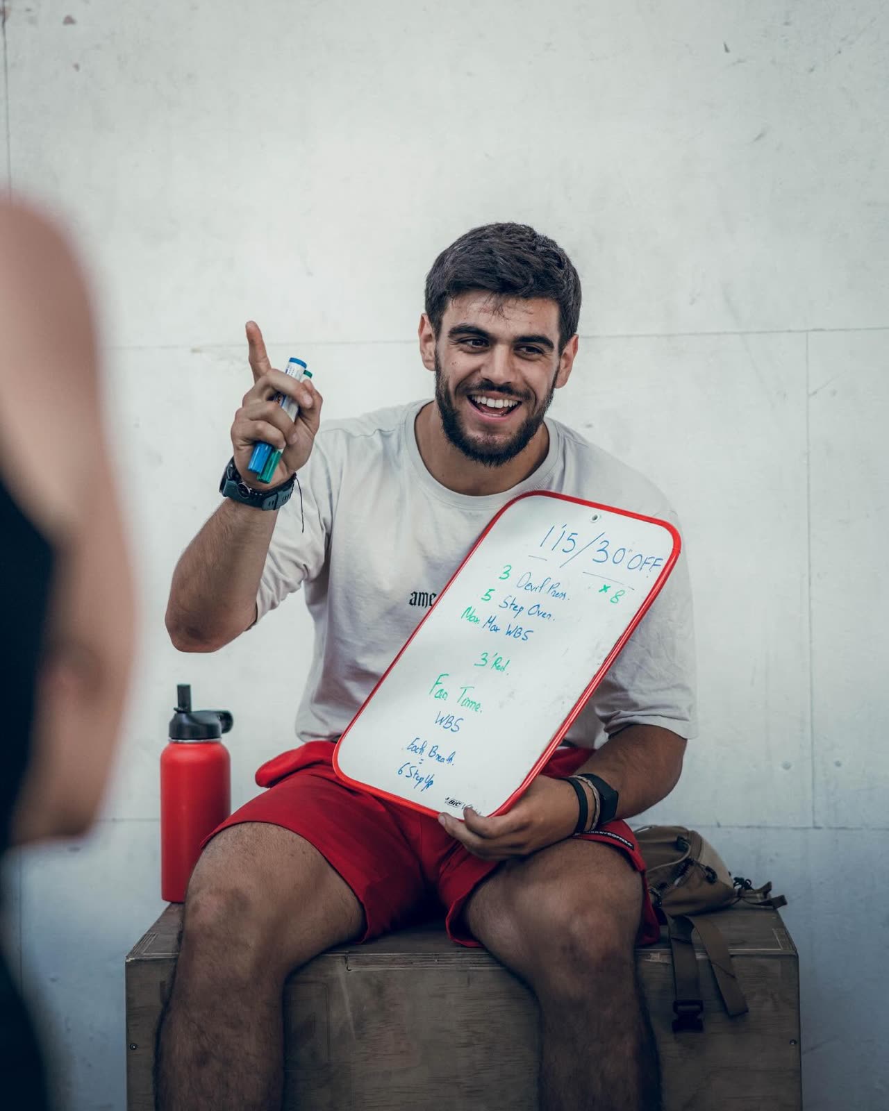 Julien Vadella, coach et co-gerant CrossFit Kurnos, souriant devant le tableau WOD